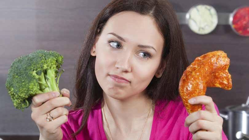 Mulher em dúvida entre carne e vegetal