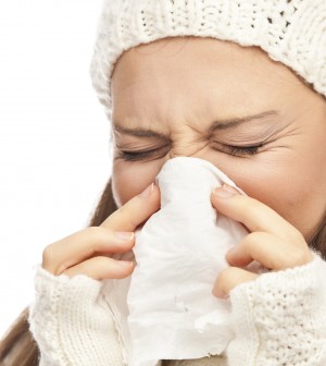 Girl in winter clothing sneezing