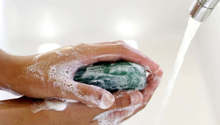 Person Washing Hands with Soap in Washbasin