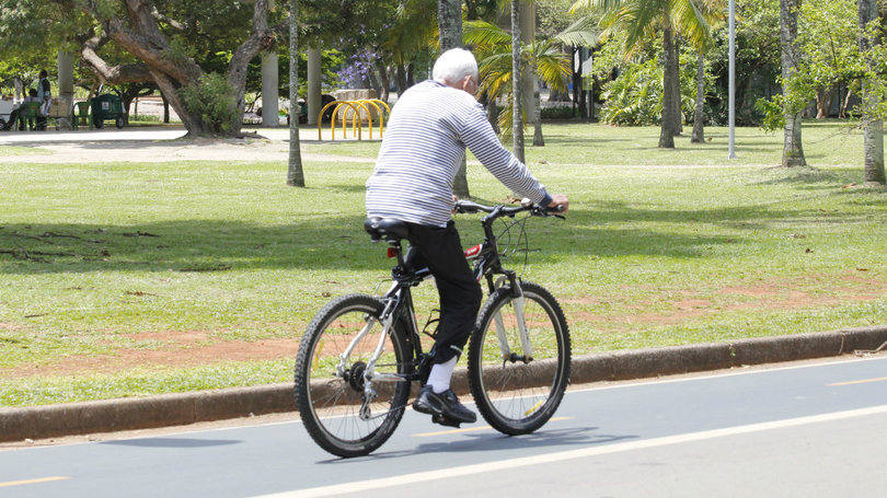 Idoso anda de bicicleta em parque