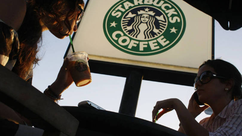 Clientes tomando bebidas do Starbucks em frente a uma cafeteria da companhia em Miami, Flórida